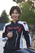 Person wearing a black and white racing jacket with red accents, standing outdoors.