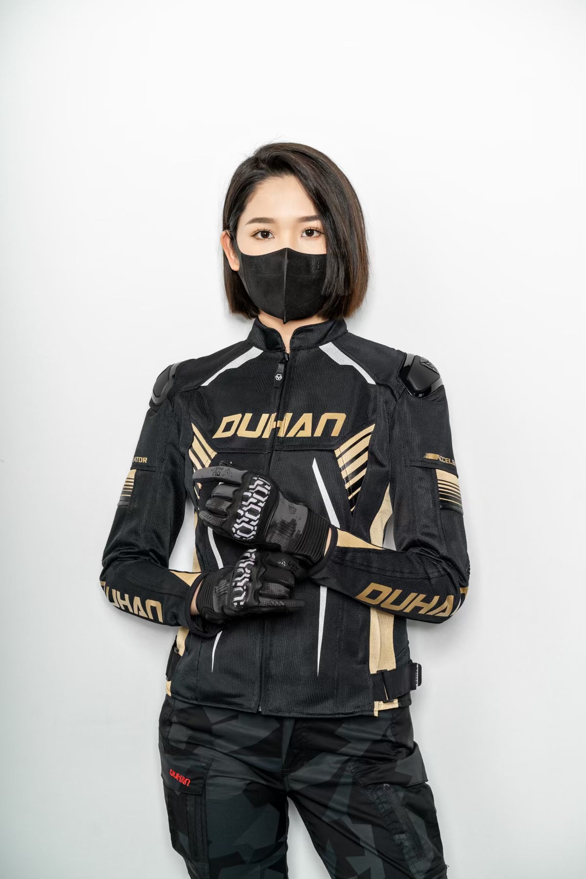 Person wearing a black and gold motorcycle suit with 'DUHAN' branding on a white background